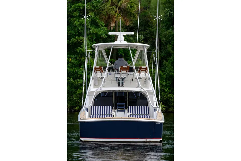Slide: The Image of 2018 Bertram 35 Flybridge yacht on water, rear view with lush greenery background. - 2