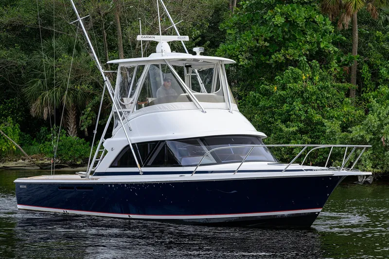 Slide: The Image of 2018 Bertram 35 Flybridge yacht cruising on a lush, green waterway. - 5