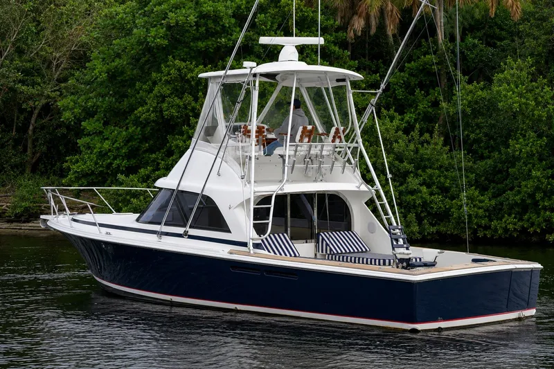 Slide: The Image of 2018 Bertram 35 Flybridge yacht cruising on a serene waterway, surrounded by lush greenery. - 11