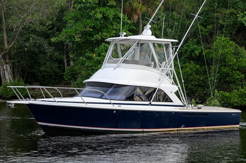 Slide: The Image of 2018 Bertram 35 Flybridge boat cruising on a calm river with lush greenery. - 9