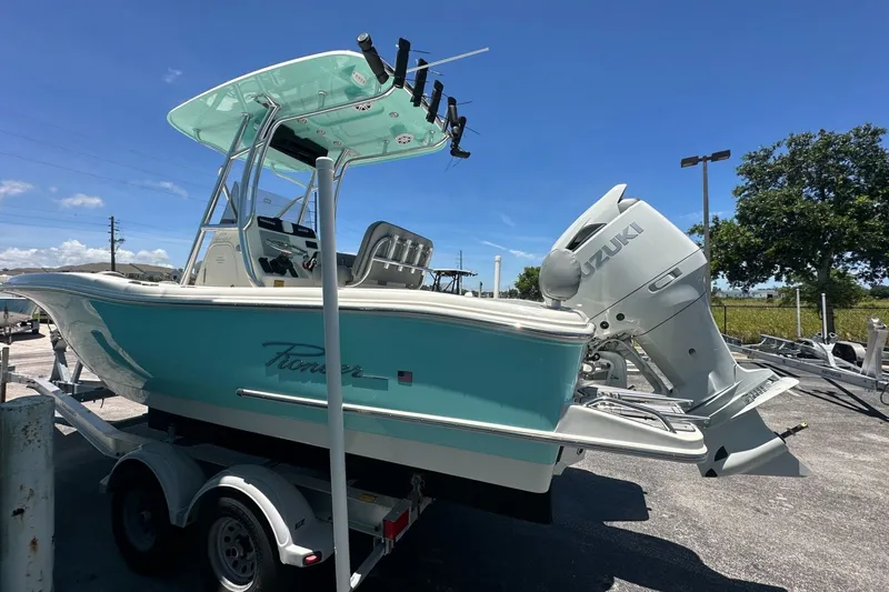 Slide: The Image of 2027 Pioneer 222 Sportfish boat with Suzuki engine on trailer, under clear blue sky. - 2