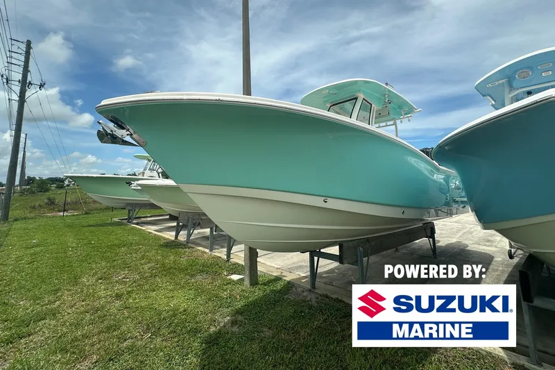 The Image of A turquoise boat on a trailer with a Suzuki Marine logo. - 0
