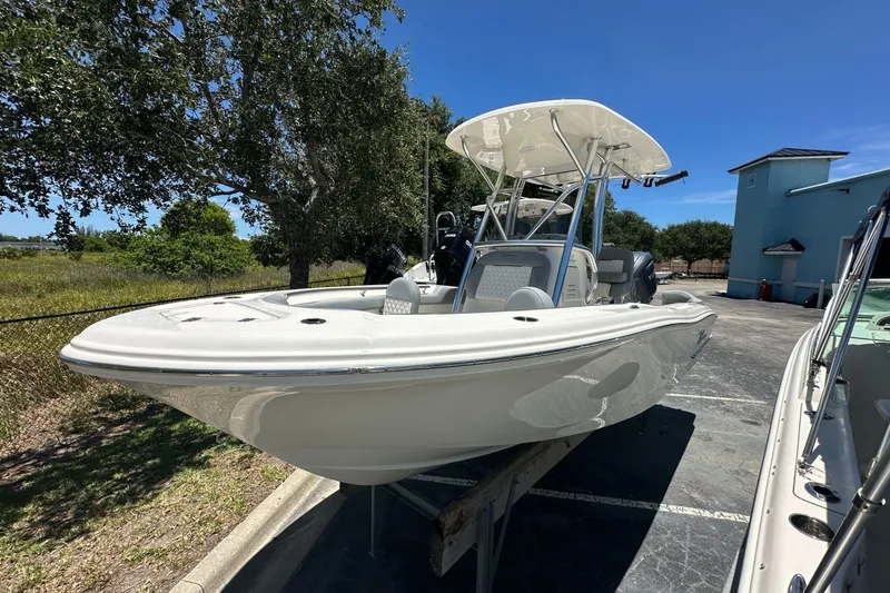 Slide: The Image of 2027 Pioneer 202 Islander boat with T-top, parked outdoors under clear blue sky. - 2