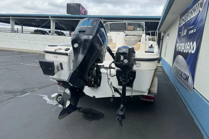 Slide: The Image of 2003 Trophy 1802 Walkaround boat with dual outboard motors in a parking lot. - 6