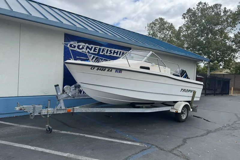 Slide: The Image of 2003 Trophy 1802 Walkaround boat on trailer outside a building with "Gone Fishing" sign. - 2