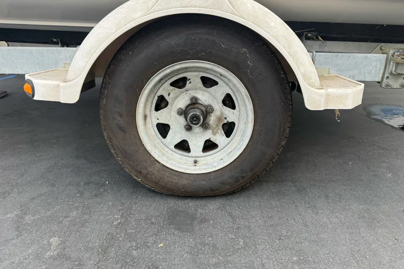 Slide: The Image of Trailer wheel of a 2003 Trophy 1802 Walkaround boat on pavement. - 33