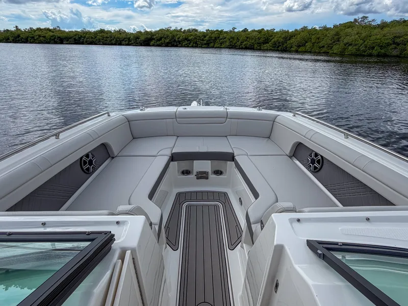 Slide: The Image of The image shows the bow of a 2027 Sea Ray SDX 290 Outboard. It features cushioned seating and is on calm water with a wooded shoreline in the background. - 19