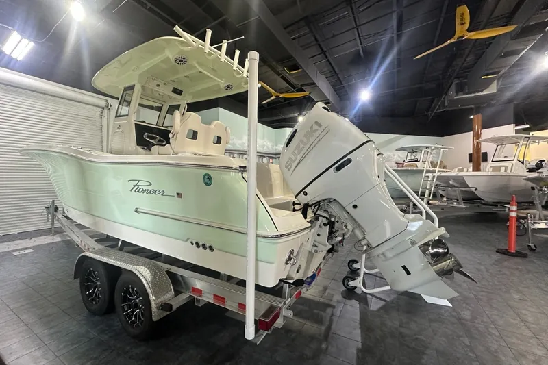 Slide: The Image of 2026 Pioneer 250 Pelagic boat with Suzuki outboard motor on display in showroom. - 2