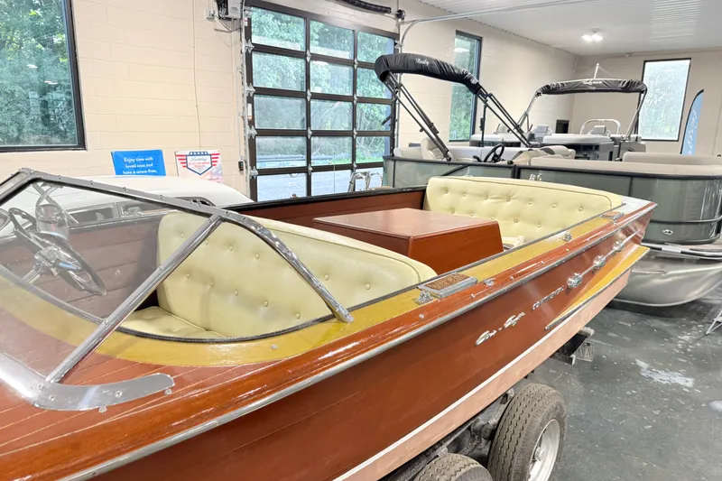 Slide: The Image of 1955 Chris Craft Chriscraft boat with classic wooden design and cream interior in a showroom. - 3