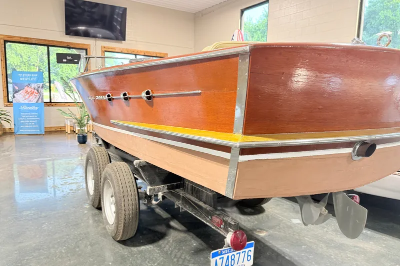 Slide: The Image of 1955 Chris Craft Chriscraft boat on trailer in showroom, showcasing classic wooden design. - 11