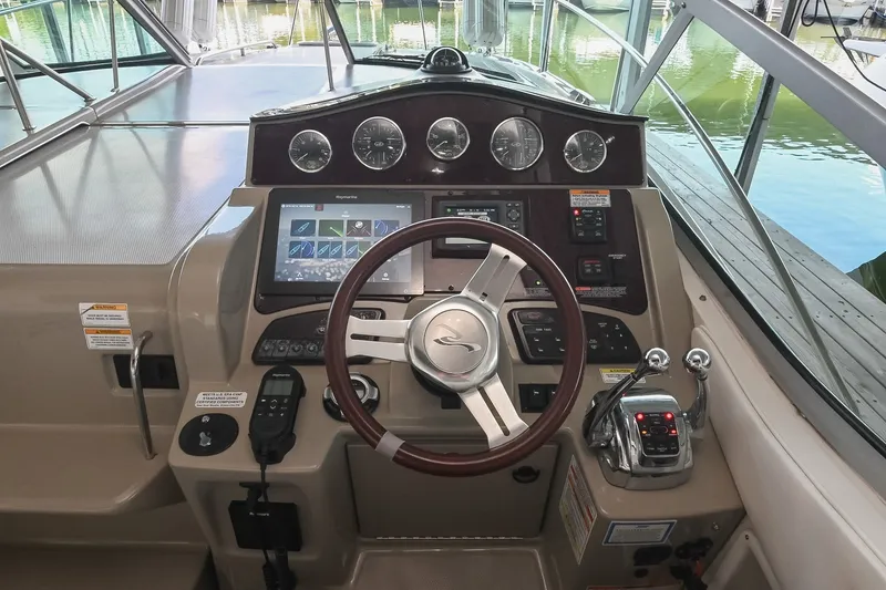 Slide: The Image of 2011 Sea Ray Sundancer 330 helm with steering wheel, gauges, and navigation controls. - 19