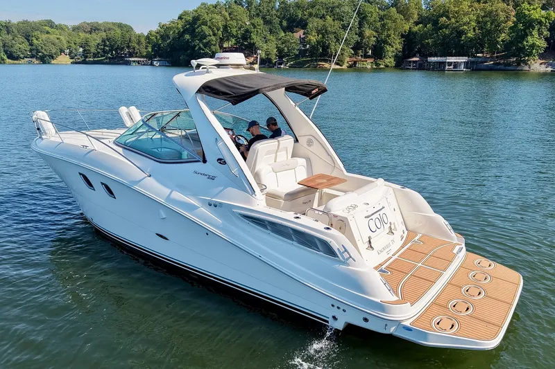 Slide: The Image of 2011 Sea Ray Sundancer 330 cruising on a serene lake with lush green shoreline. - 14
