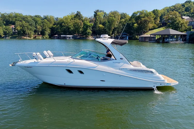 Slide: The Image of 2011 Sea Ray Sundancer 330 yacht cruising on a serene lake with lush green surroundings. - 13