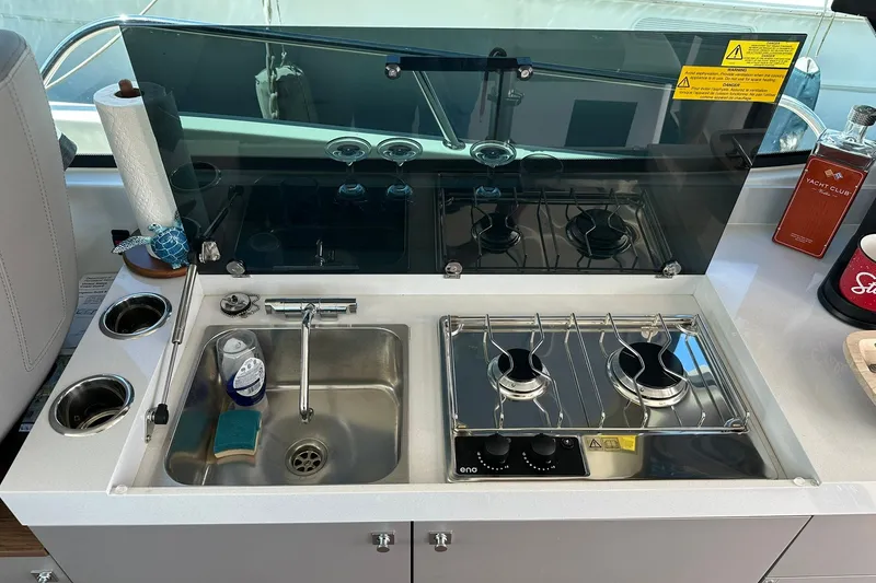 Slide: The Image of Compact kitchen area on 2024 Beneteau Antares 11 Fly with sink and dual-burner stove. - 60