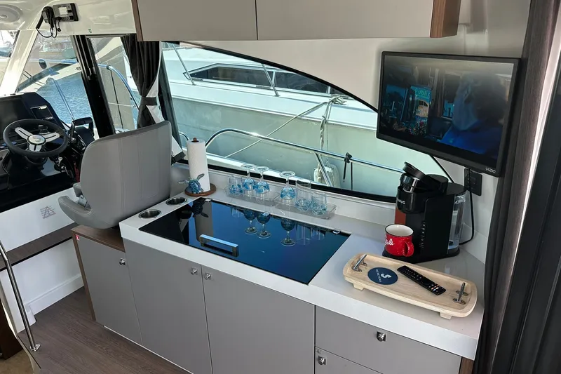 Slide: The Image of Interior of 2024 Beneteau Antares 11 Fly, featuring helm, kitchenette, and TV. - 58