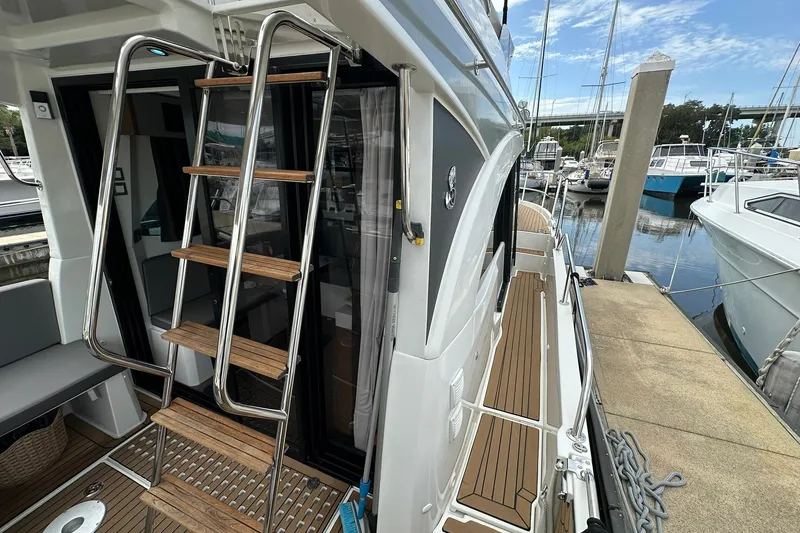 Slide: The Image of 2024 Beneteau Antares 11 Fly yacht docked, featuring sleek design and wooden ladder. - 18