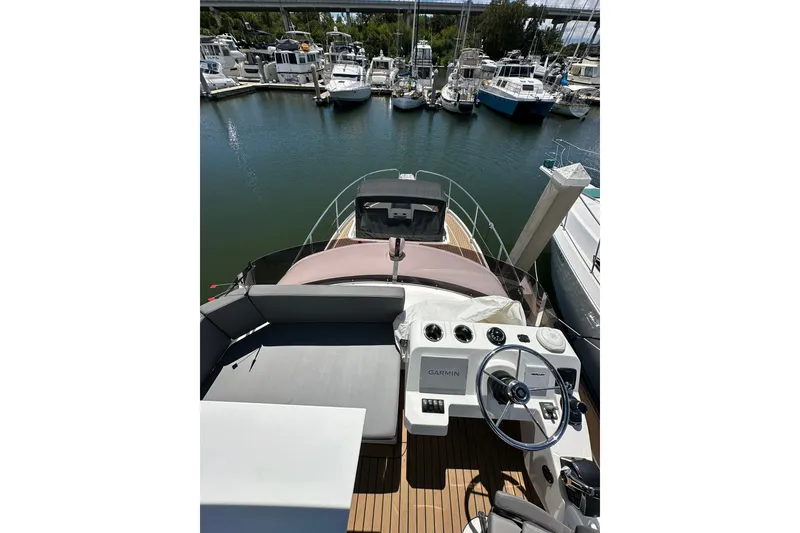 Slide: The Image of 2024 Beneteau Antares 11 Flybridge view, showcasing helm and marina backdrop. - 29
