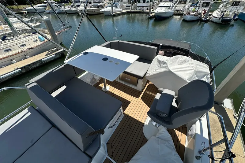 Slide: The Image of 2024 Beneteau Antares 11 Flybridge with seating area, table, and marina view. - 22