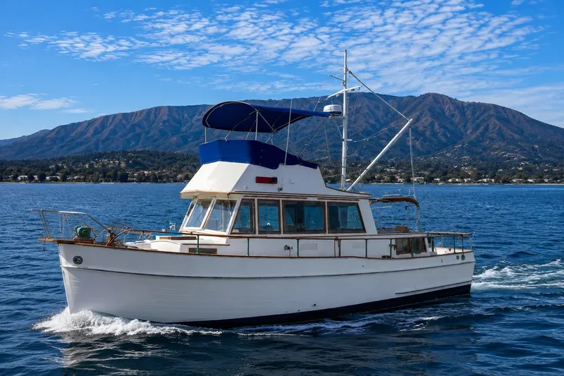 Slide: The Image of 1978 Grand Banks 36 Classic yacht cruising on a scenic lake with mountains in the background. - 1