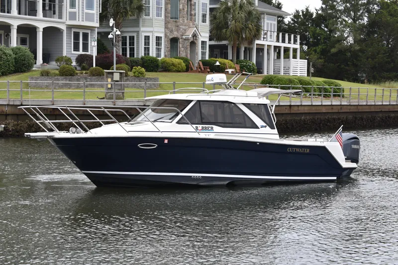 The Image of 2022 Cutwater C-248 Coupe boat cruising near waterfront homes. - 2