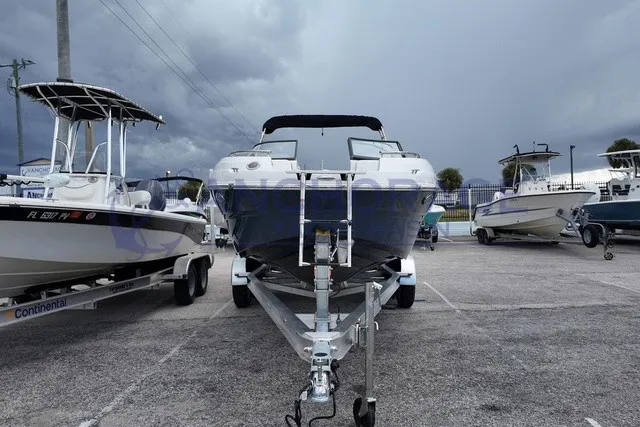 Slide: The Image of A 2027 Stingray 22DC boat on a trailer in a parking lot, surrounded by other boats. - 2
