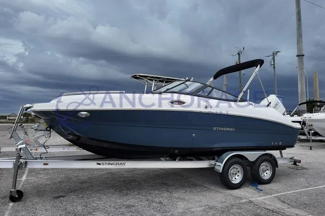 Slide: The Image of Stingray 22DC 2027 on a trailer, featuring a blue hull and black bimini top. - 1