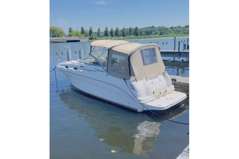 Slide: The Image of 2003 Sea Ray Sundancer 260 boat docked on a calm lake under clear skies. - 1