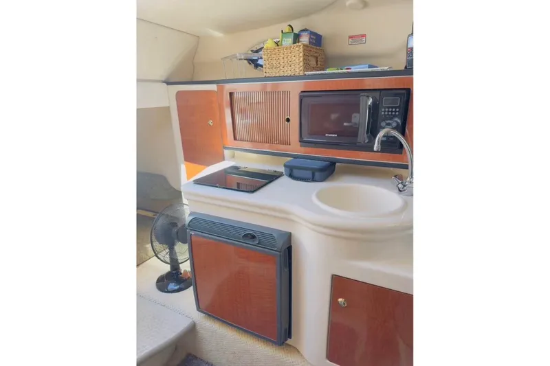 Slide: The Image of 2003 Sea Ray Sundancer 260 cabin kitchen with microwave, sink, and storage cabinets. - 6
