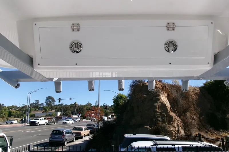 Slide: The Image of 2026 Sea Fox 248 Commander boat storage compartment with rod holders, parked near a road. - 20