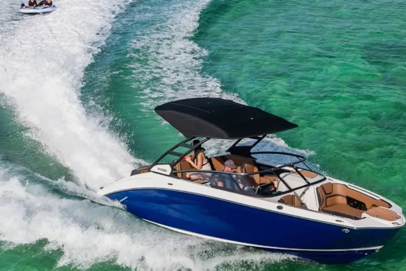 Slide: The Image of 2026 Yamaha Boats 252SD cruising on clear turquoise water, towing a tube. - 2