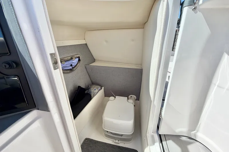 Slide: The Image of 2020 Cobalt 23SC boat interior with compact marine toilet and storage area. - 16