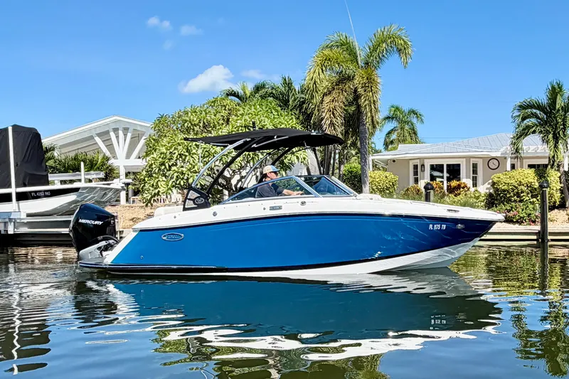 The Image of 2020 Cobalt 23SC boat on calm water, surrounded by palm trees and a sunny sky. - 0