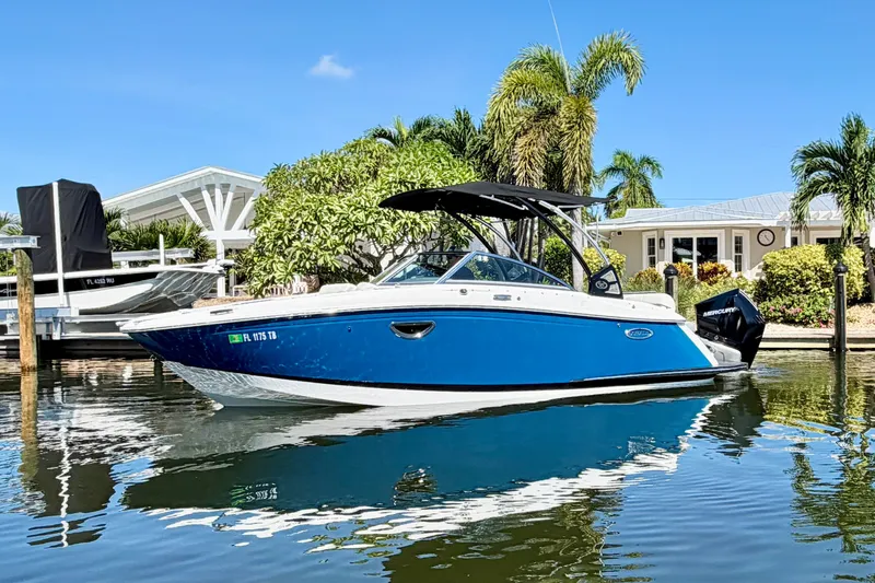 Slide: The Image of 2020 Cobalt 23SC boat docked by a waterfront home, surrounded by palm trees. - 5