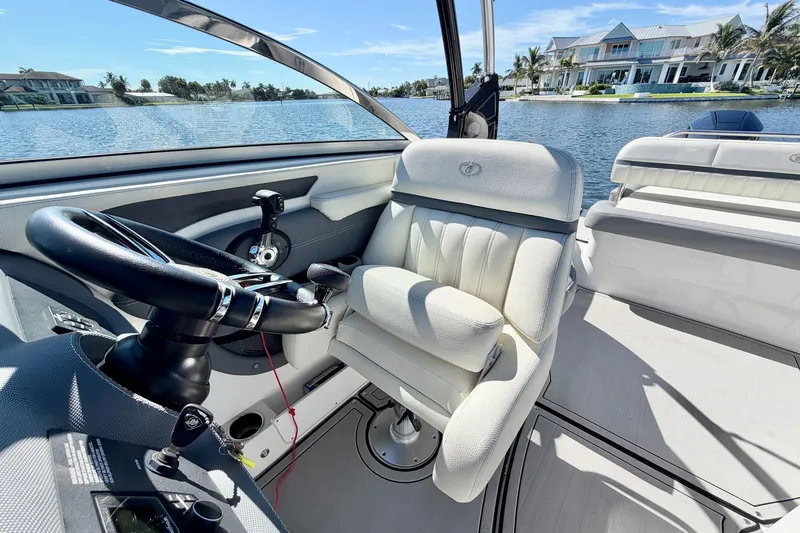 Slide: The Image of 2020 Cobalt 23SC boat interior with steering wheel and luxurious seating by waterfront homes. - 18