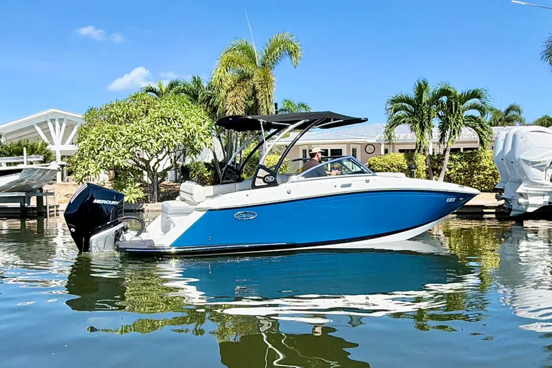 Slide: The Image of 2020 Cobalt 23SC boat on water, blue hull, palm trees in background. - 1