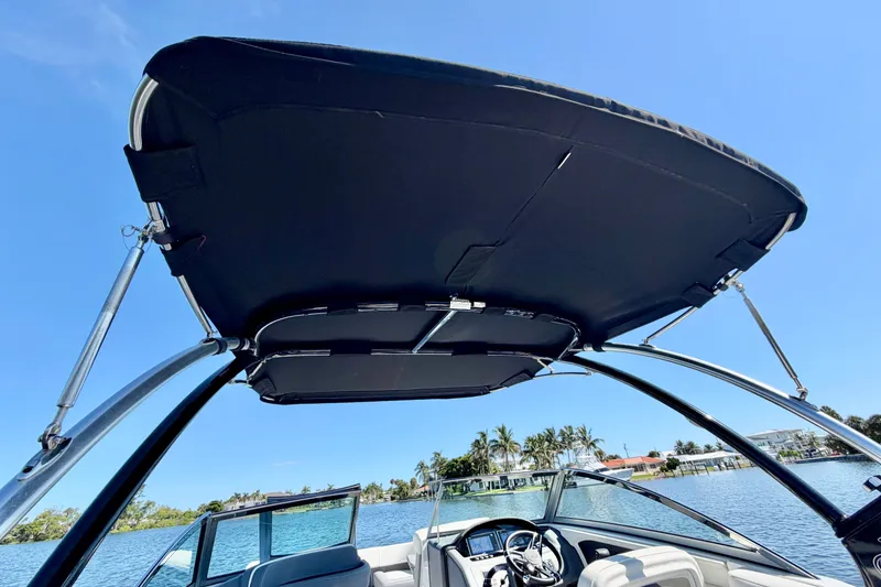 Slide: The Image of 2020 Cobalt 23SC boat with bimini top, steering wheel, and clear blue sky background. - 17