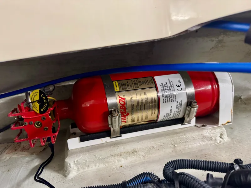 Slide: The Image of A fire extinguisher is mounted inside a boat, surrounded by cables and hoses. - 37