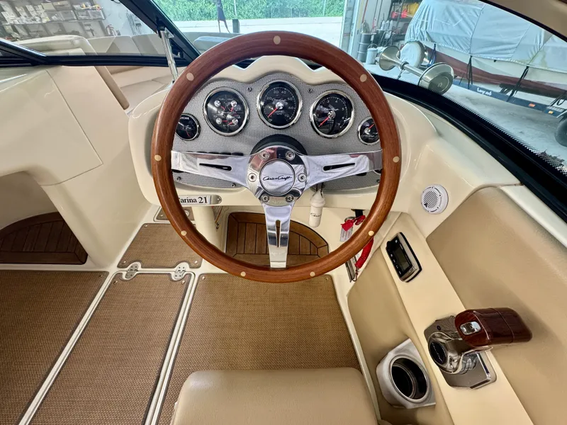 Slide: The Image of The image shows the cockpit of a 2016 Chris-Craft Carina 21 with a stylish wooden steering wheel. - 26