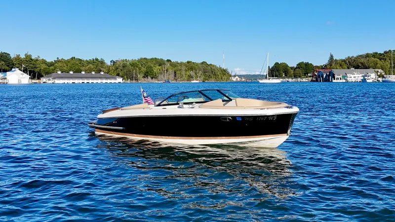 Slide: The Image of A sleek 2016 Chris-Craft Carina 21 boat on calm water, surrounded by green landscape. - 16