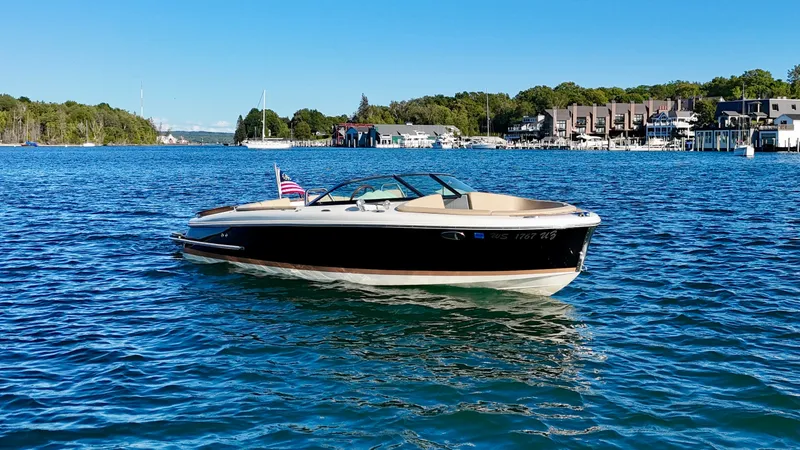 Slide: The Image of A 2016 Chris-Craft Carina 21 on calm waters, featuring an American flag. - 14