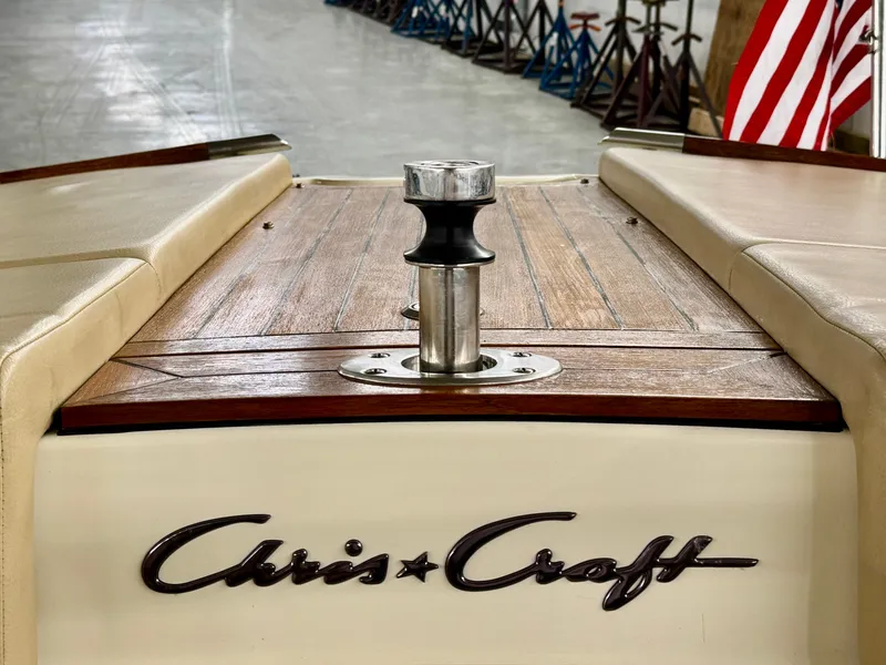 Slide: The Image of The image shows the stern of a Chris-Craft Carina 21 boat with a wooden deck and American flag. - 22