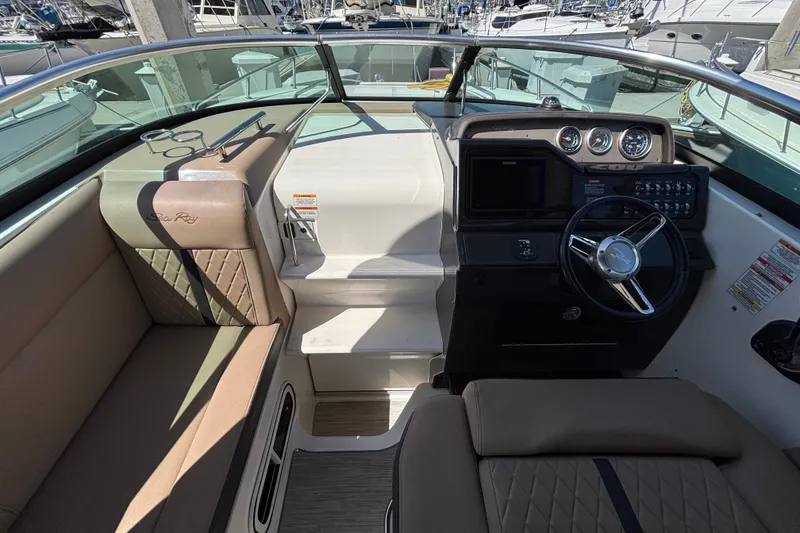 Slide: The Image of 2016 Sea Ray Sundancer 260 cockpit with steering wheel, gauges, and seating in a marina setting. - 10