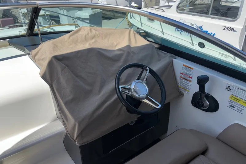 Slide: The Image of 2016 Sea Ray Sundancer 260 helm with covered dashboard and steering wheel. - 21
