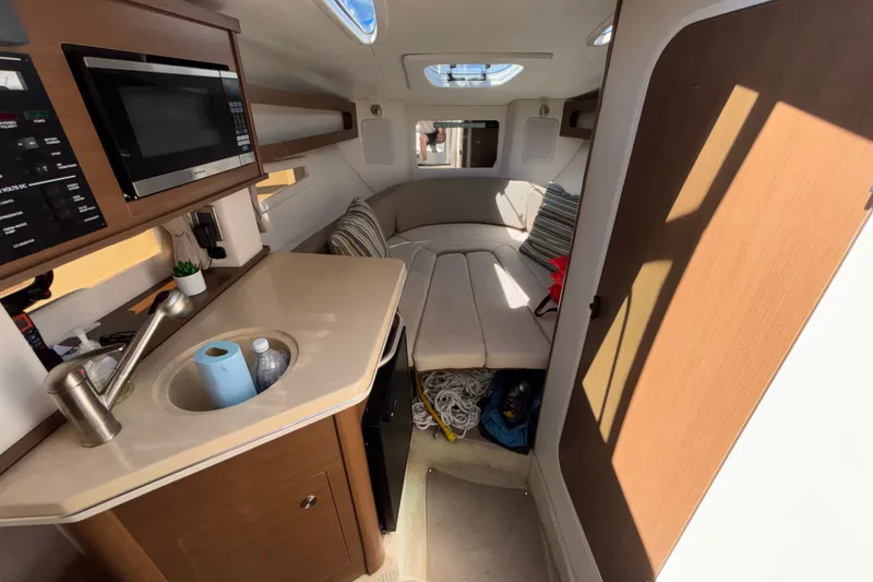 Slide: The Image of Interior of 2016 Sea Ray Sundancer 260, featuring kitchenette and cozy seating area. - 13