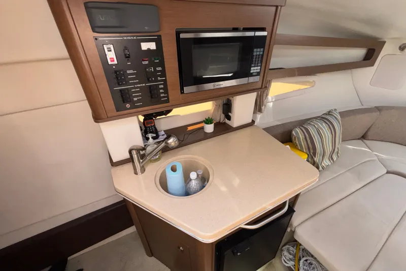 Slide: The Image of Compact galley in 2016 Sea Ray Sundancer 260 with microwave, sink, and seating area. - 14