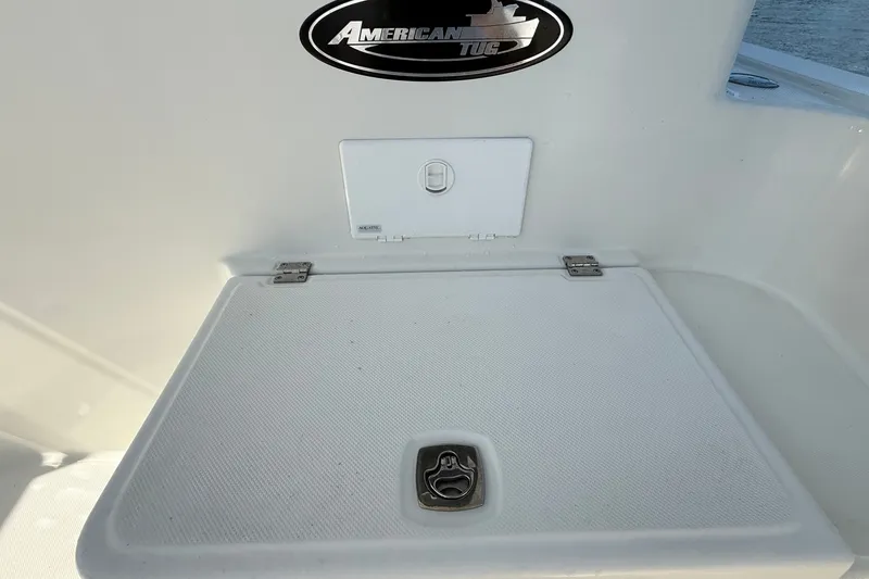 Slide: The Image of American Tug 365 boat deck detail, 2012 model, featuring storage compartment and logo. - 35