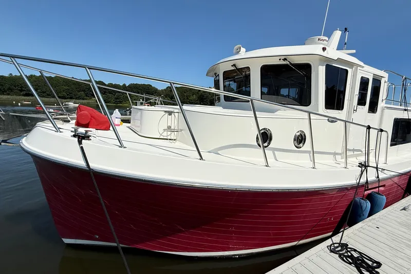 Slide: The Image of 2012 American Tug 365 boat docked, featuring a red hull and white cabin. - 1