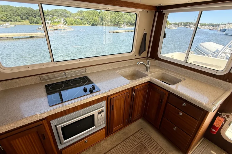 Slide: The Image of American Tug 365 (2012) galley with stove, microwave, and scenic water views. - 53