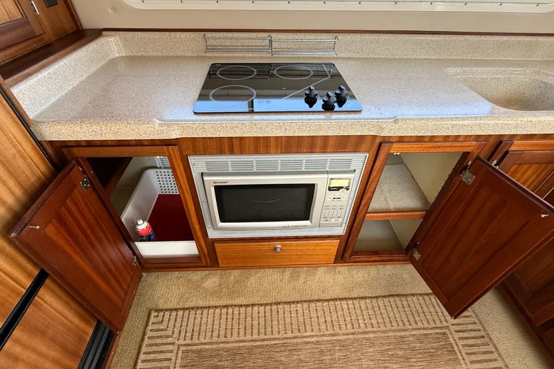 Slide: The Image of Kitchen area of 2012 American Tug 365 with stove, microwave, and open cabinets. - 54