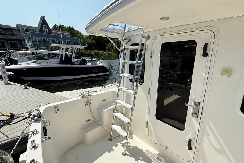 Slide: The Image of American Tug 365 (2012) docked, featuring a ladder and door, with boats and buildings nearby. - 15
